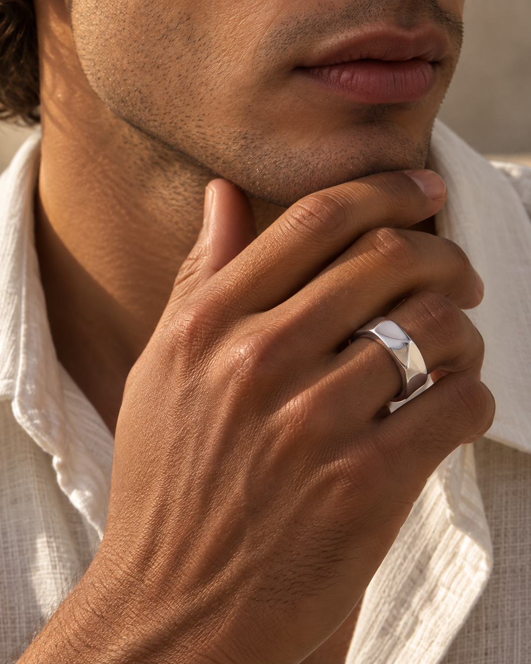 Ace Ring für Herren aus hochglanzpoliertem silberfarbenem Stahl, in Nahaufnahme am Kinn