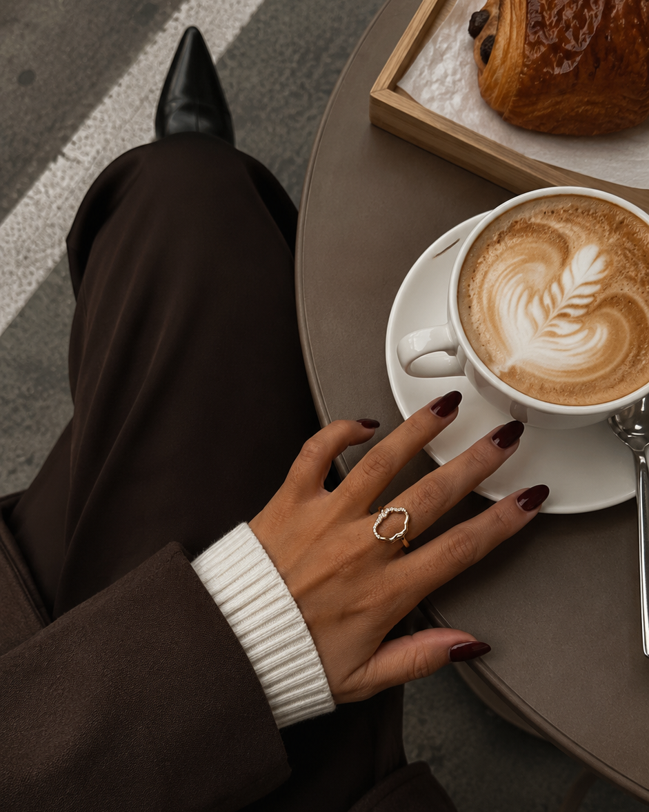 Nashira Ring i 18K forgyldt sterlingsølv med zirkoner, fotograferet på café