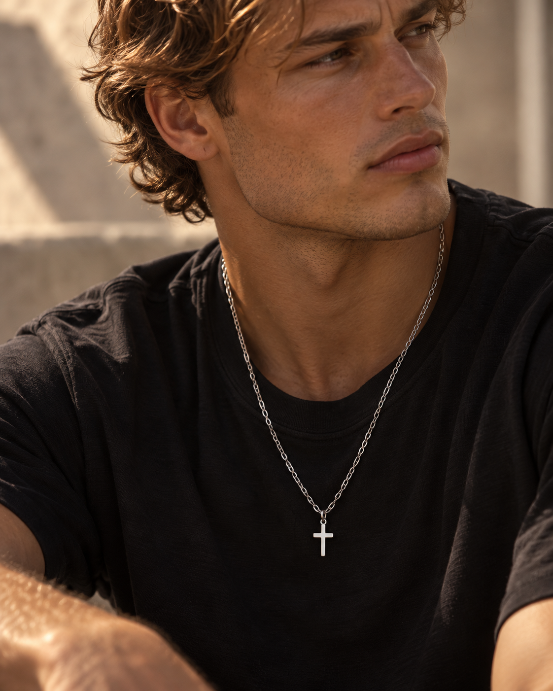 Saint necklace with 925 sterling silver cross worn by a man at sunset