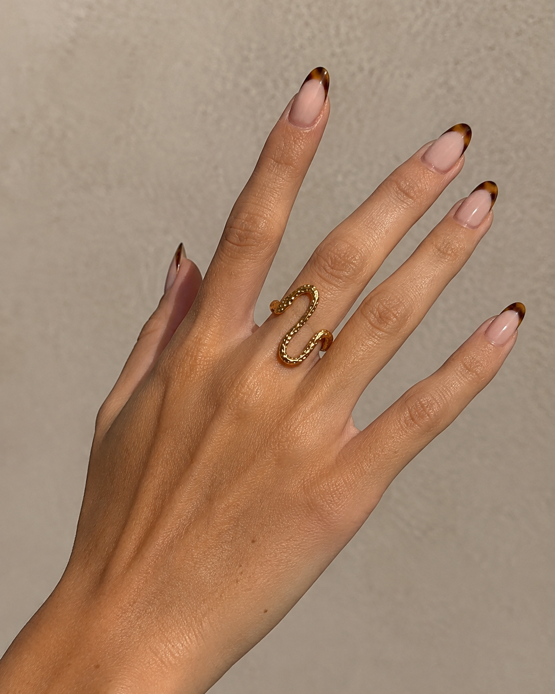 Vela gold-plated ring with a wavy shape worn on the hand
