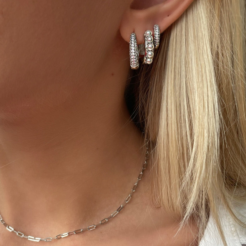 Poise Earring is a breathtaking earring filled with clear cubic zirconia. The earring is a chunky hoop which makes it easy to style alone or together with other hoops. An absolute must-have
